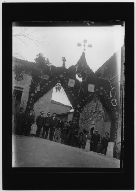 Gruppo di persone sotto la porta trionfale allestita in occasione della visita del vescovo a Bidogno