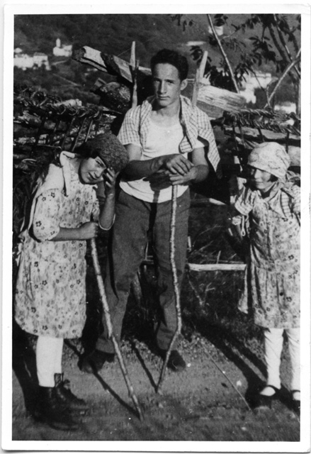 Due bambine e un uomo in posa mentre trasportano legna
