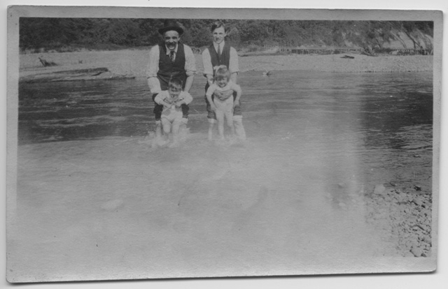 Due uomini con due bambini sulla spiaggia