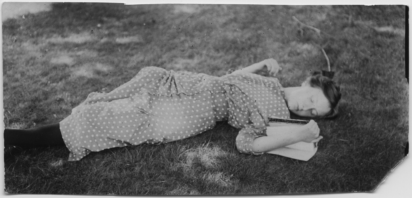 Gina Maria Rossi mentre legge stesa sopra a un prato