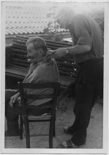 Pietro Marioni mentre taglia i capelli a Natale Canonica