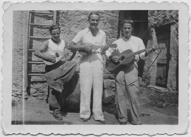 Tre uomini con chitarra e mandolino in piazza Gransch a Comano
