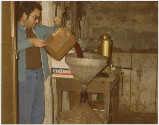 Uomo mentre versa del vino in una damigiana