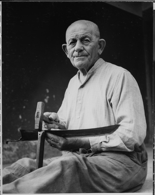 Uomo mentre affila la falce a Roveredo