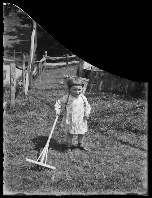 Bambina in posa con gerla e rastrello