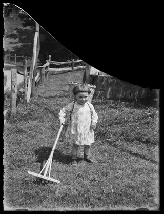 Bambina in posa con gerla e rastrello