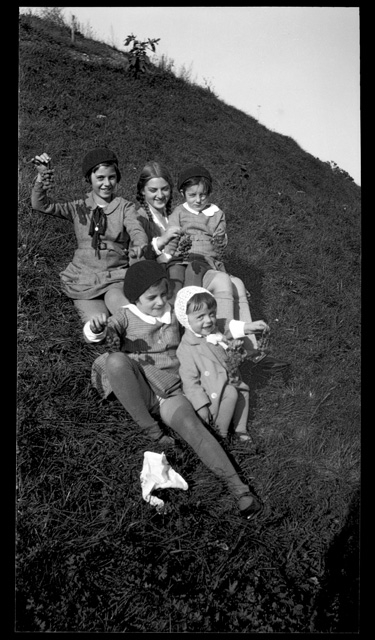 Bambine in posa sopra a un prato con grappoli d'uva