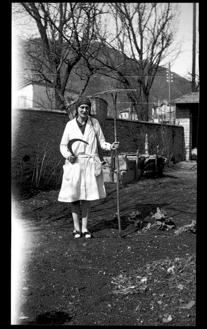 Giovane donna in posa con falce e rastrello