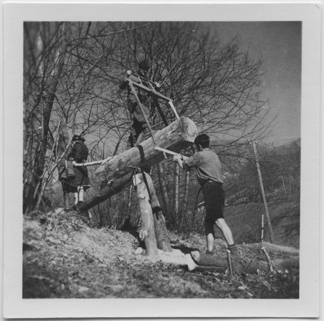 Uomini che segano un tronco posto su una pietica con una sega intelaiata