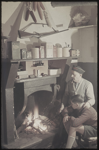 Uomo con ragazzo davanti al camino della cucina della famiglia Bernasconi ad Agno