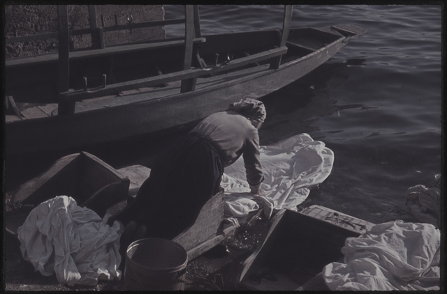 Donna mentre fa il bucato sulle rive del Cassarate