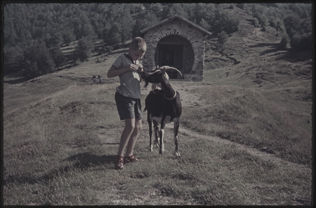 Ragazzo con capra davanti alla cappella sui monti di Cimadera