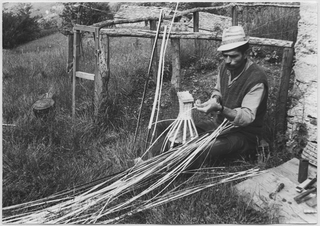 Cestaio mentre intreccia una gerla ai monti di Brena