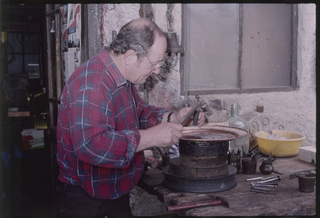 Fabbro artigiano mentre modella il bordo di un vassoio