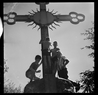 Ragazzi mentre si arrampicano sulla croce dell'oratorio di San Bernardo