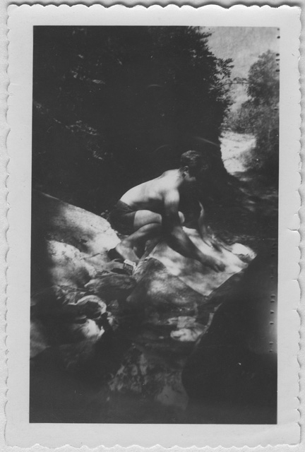 Ragazzo mentre lava dei panni al fiume