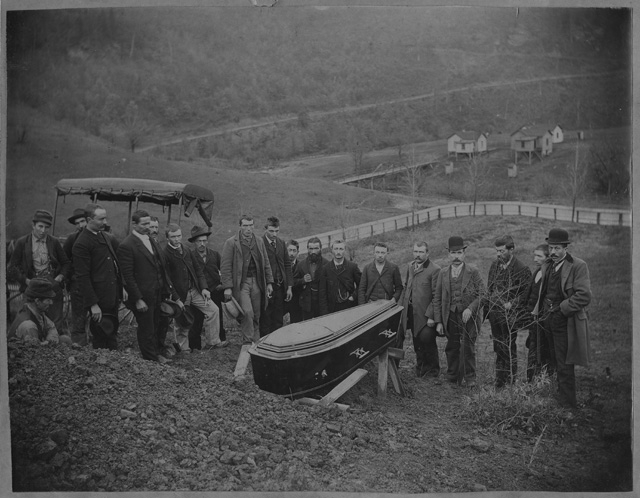 Gruppo di uomini attorno a una bara